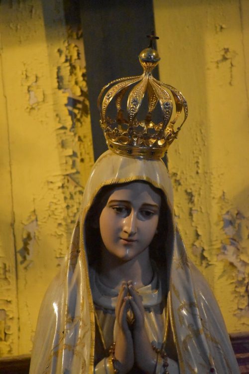 our lady of fatima statuette with crown against shabby wall